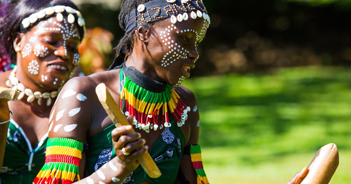 Women adorned in traditional attire and tribal face paint perform an energetic cultural dance, showcasing The Gambia’s vibrant heritage and community spirit.