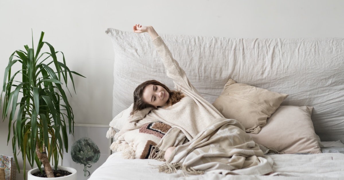 a woman laying on a bed with a blanket