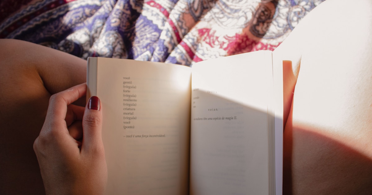 a person is reading a book on a bed