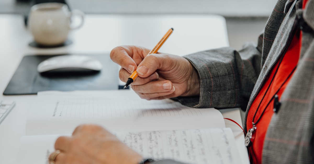 a person sitting at a desk writing on a piece of paper