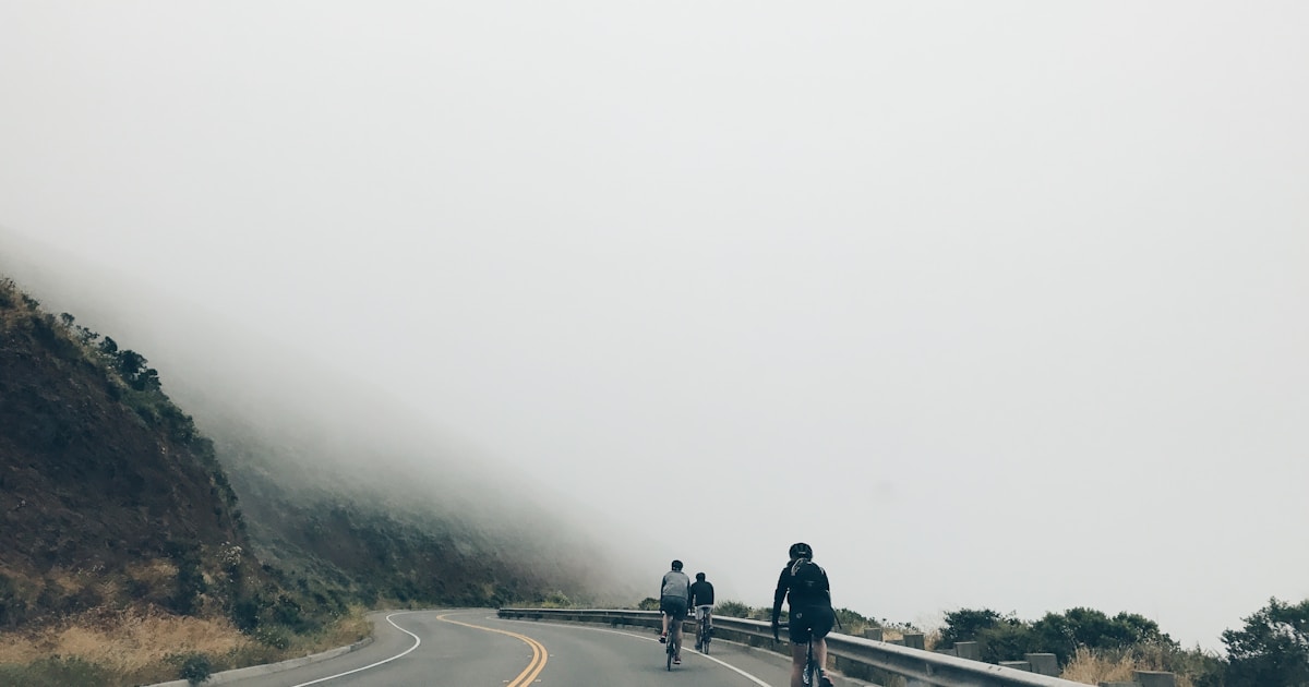 three men biking on asphalt road