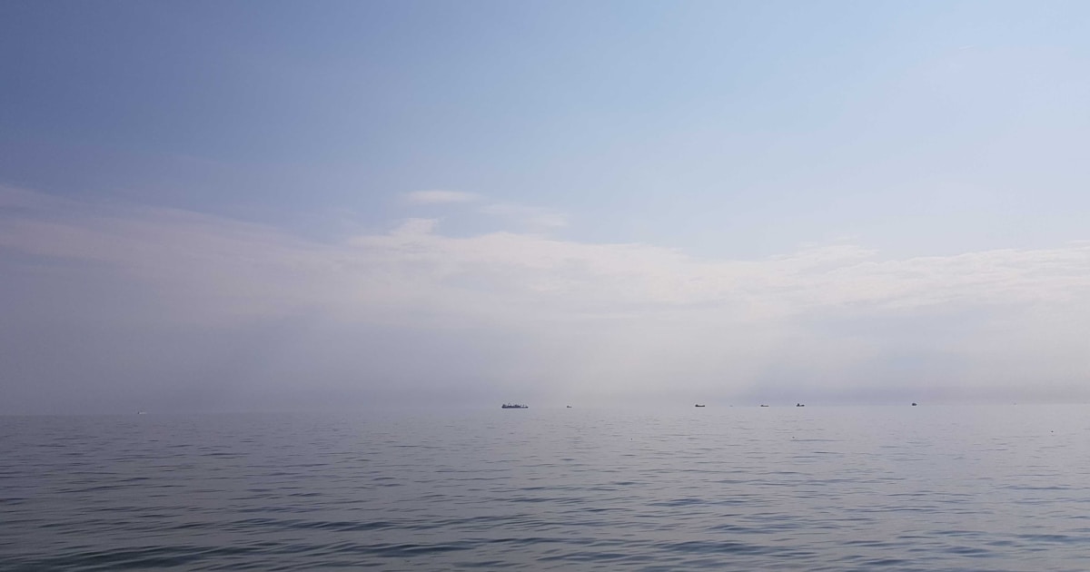 body of water under white sky during daytime
