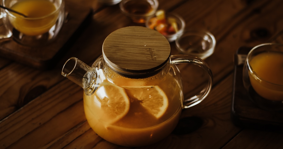 A glass tea pot filled with orange juice