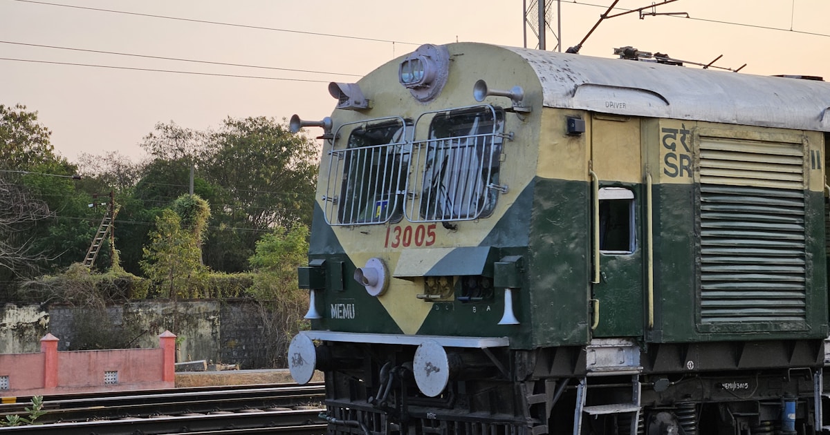 A green and yellow train traveling down train tracks