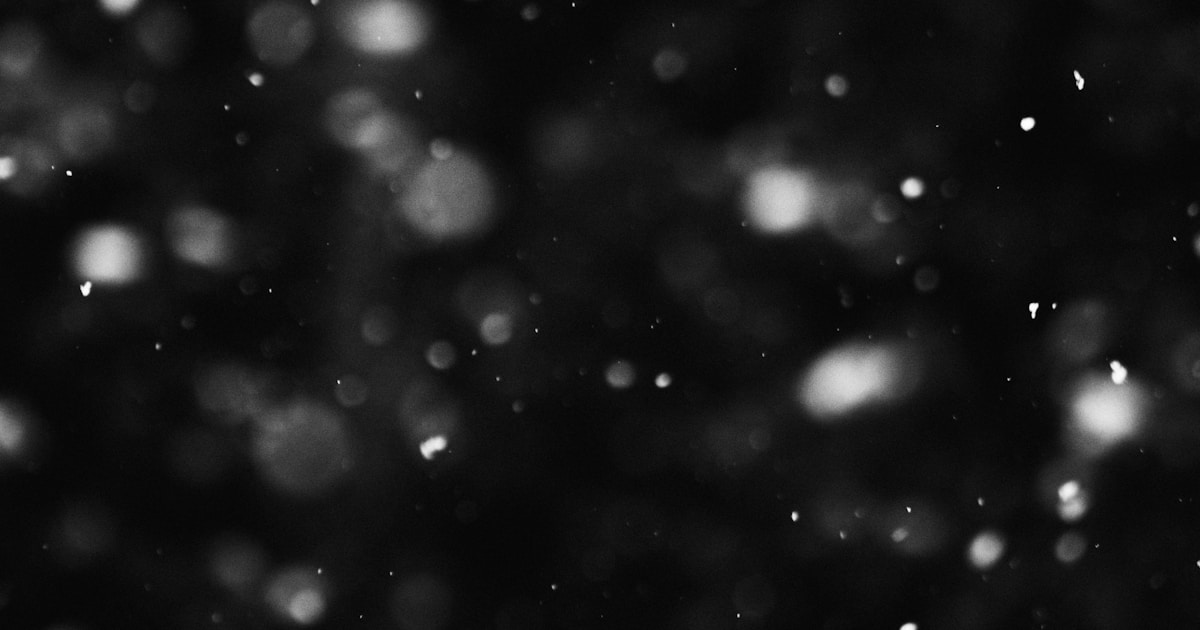 a black and white photo of snow falling