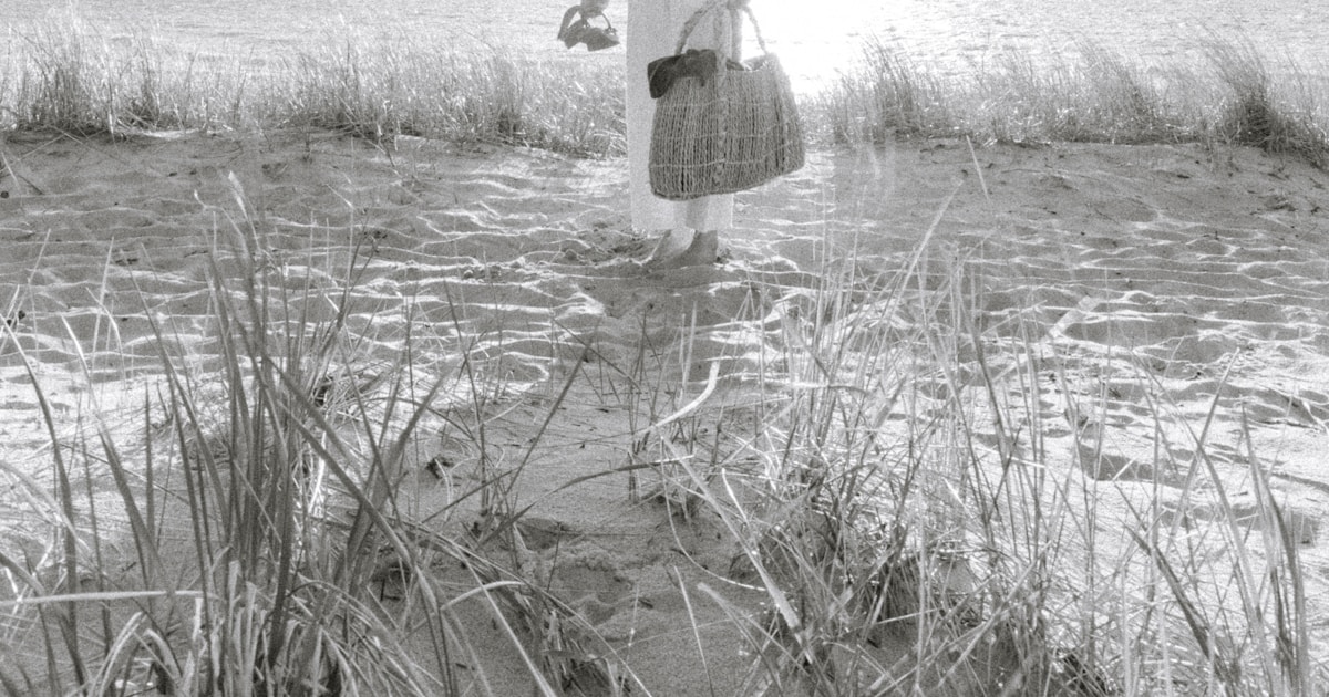 a black and white photo of a person standing on a beach