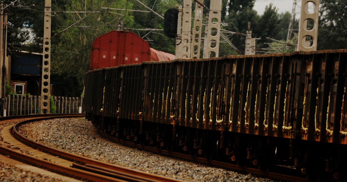a train traveling down train tracks next to a forest