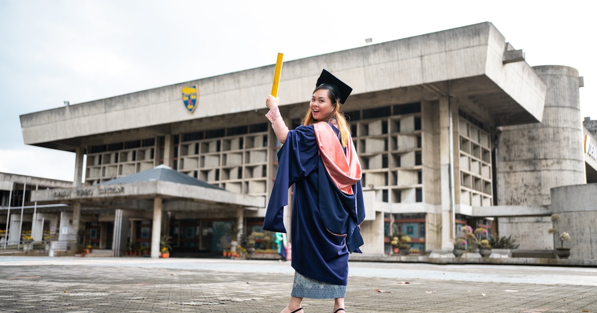 a woman in a graduation gown holding a bat