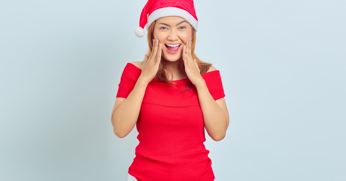 Beautiful young woman with short hair wearing christmas hat surprised with open mouth. christmas concept