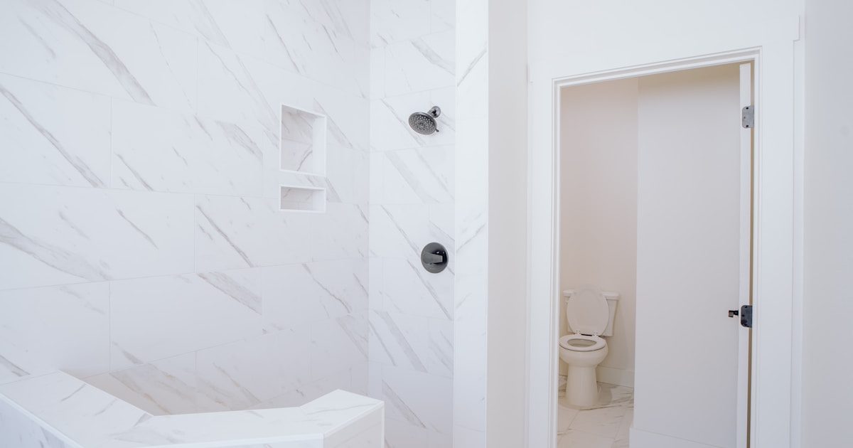 a white bathroom with a toilet and a shower