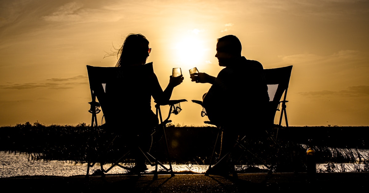 a man and woman sitting on a chair at the beach