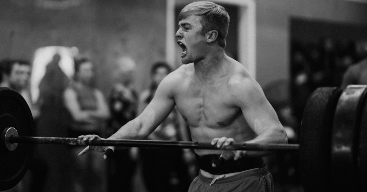 a man holding a barbell in a gym